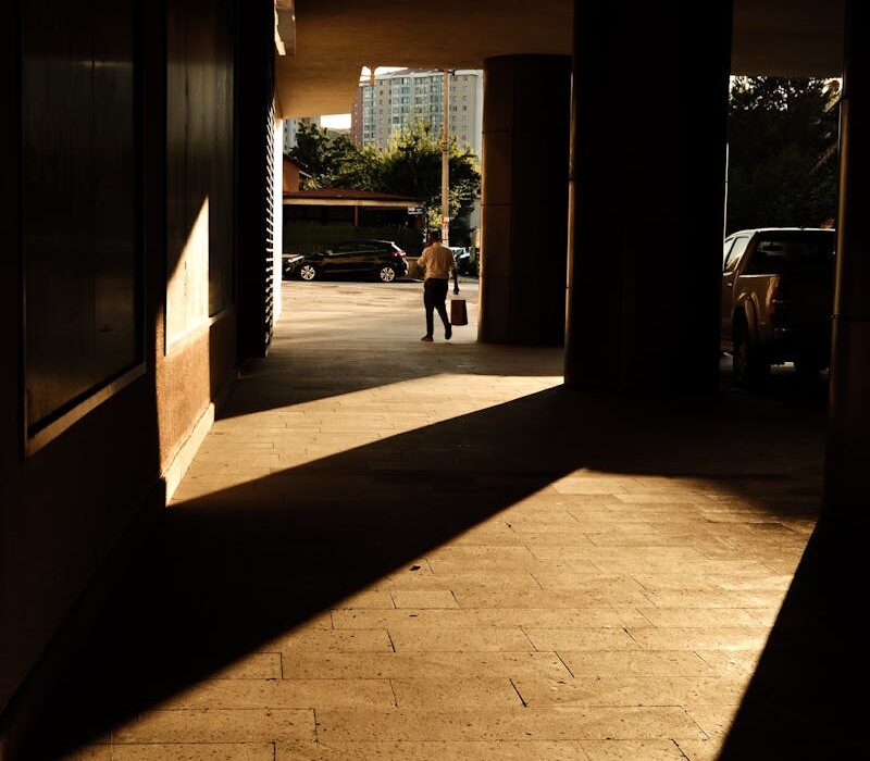 Glimpse of a cityscape through an architectural passage with striking shadows.