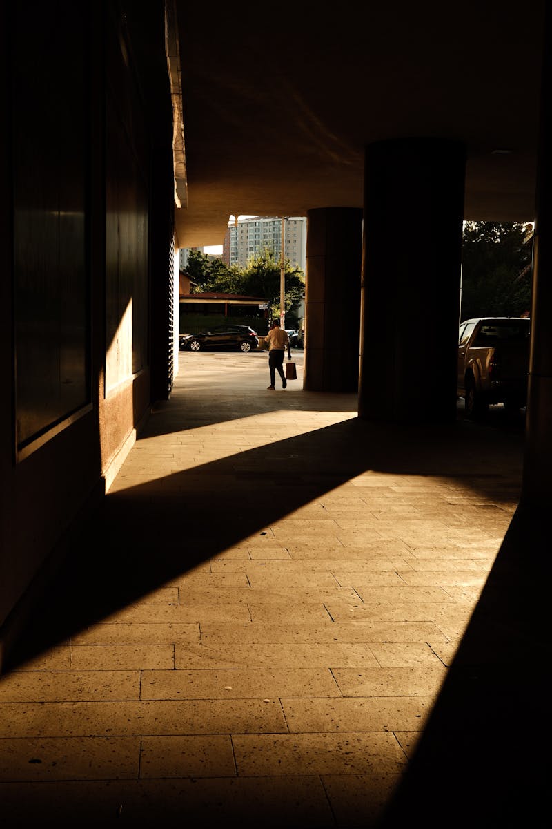 Glimpse of a cityscape through an architectural passage with striking shadows.