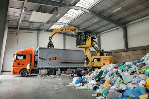 a large truck with a load of trash in a warehouse